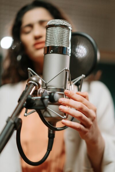 Singer behind large diaphragm mic singing. Mic is in focus singer is slightly out of focus. 