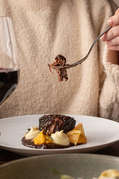 a woman eating an elevated plate of steak