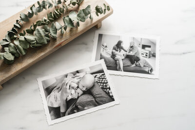 Two black and white photographs of tender family moments displayed on a marble surface.