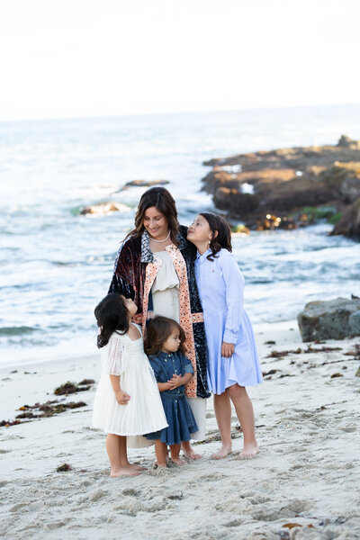 Mom and her 3 daughters standing on a beach looking at each other during family photography session with boise's best family photographer Tiffany Hix