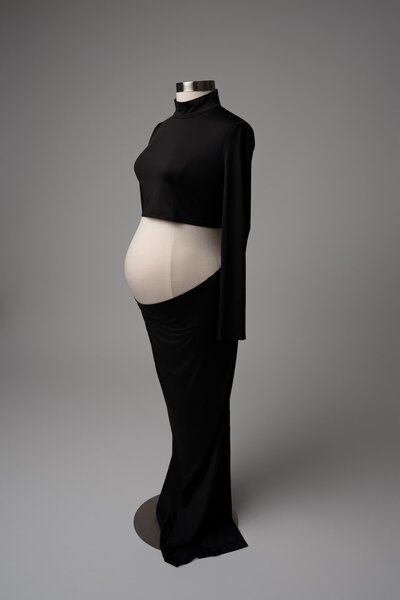 Fitted black dress with minimalist belly reveal in side-profile pose