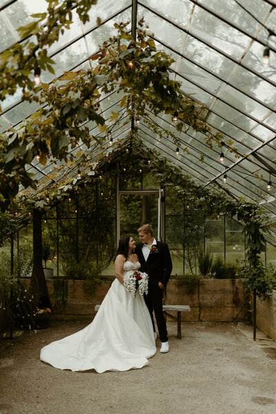 Couple in their wedding attire in a greenhouse at the Glass House Creative Community in Zeeland, Michigan.
