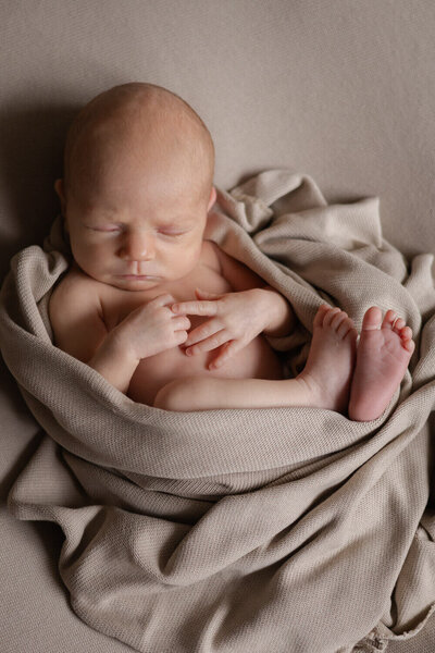 Baby in een ontspannen pose, gefotografeerd door Newborn Fotograaf Tilburg. Newbornshoot thuis.
