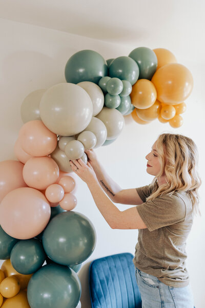 Sara Saxon installing balloon garland for Lux Aeir