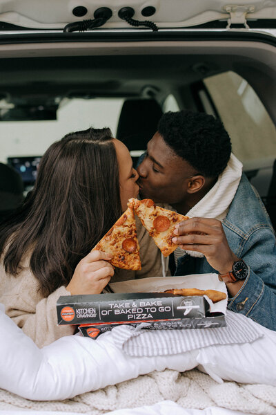 couple kissing with pizza