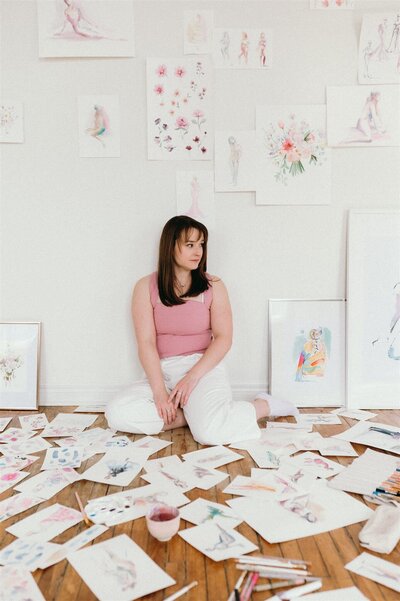 Stephanie Anne Illustration workspace in Quebec, with numerous watercolor sketches spread across a wooden floor, showcasing her live event sketching process