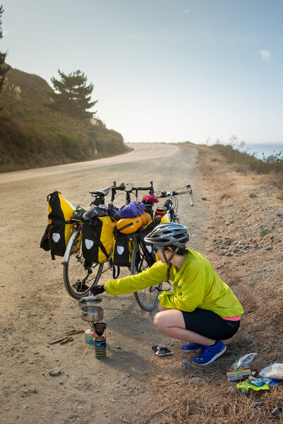 Becky makes coffee next to her lpaded bicycle before taking off on another long day of bike touring.