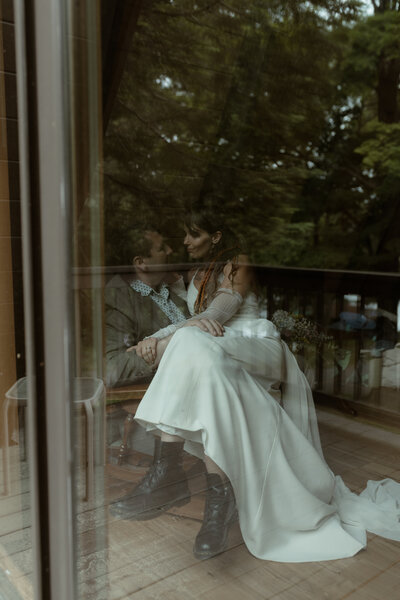 couple enjoying pizza and laughing together inside a cozy wood-paneled cabin kitchen during their intimate elopement getaway