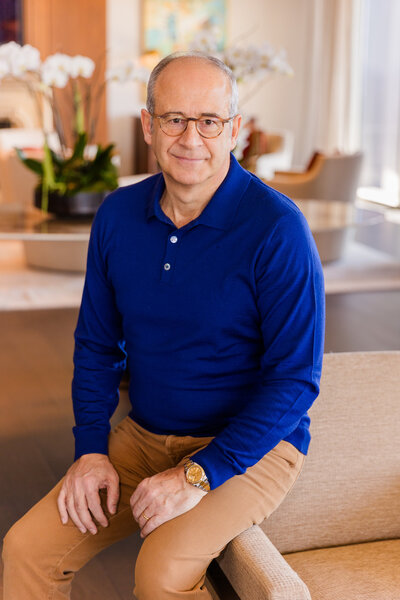 Ahmet Bozer wearing a blue top and beige pants, sitting on a sofa armchair during his personal brand photo session in Atlanta Buckhead