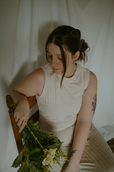 Elopement photographer siting in chair holding flowers