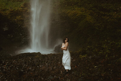 girl standing in white dress next to waterfall in the columbia river gorge