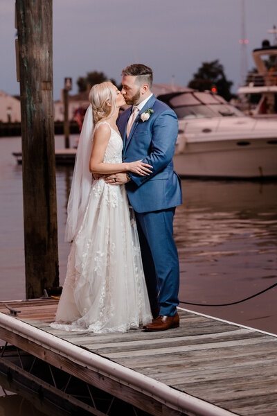 A newly wedded couple shares a kiss on the dock at Chesapeake Inn in Chesapeake City, Maryland. Photo taken by Christopher Ginn Studios.