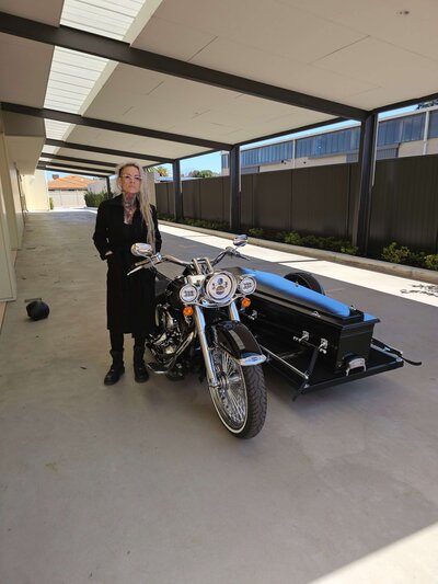 Kristy standing beside the Harley Davidson hearse, showing the personal and respectful service Caskets and Chrome provides.