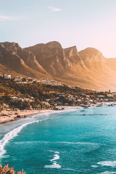Beautiful view of Camps Bay, South Africa at Sunset with mountains just behind the town overlooking the bay