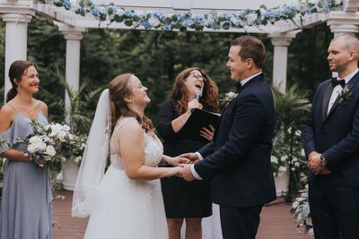 Officiant laughing with bride and groom at altar