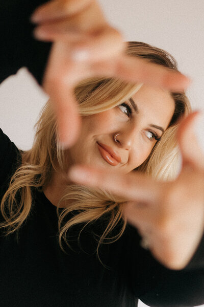 Portrait of photographer Tarah Shea in spotlight with relaxed, editorial pose, West Coast wedding photographer branding image