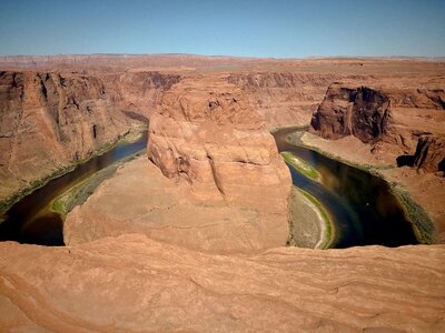 Scenic view of Horseshoe Bend in Page, Arizona, showing the dramatic curve of the Colorado River winding through towering red rock canyons under a clear blue sky.
