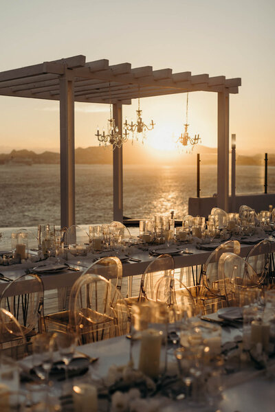 Luxury wedding in Mexico with chandeliers over glamorous tablescapes while the sun sets in the background