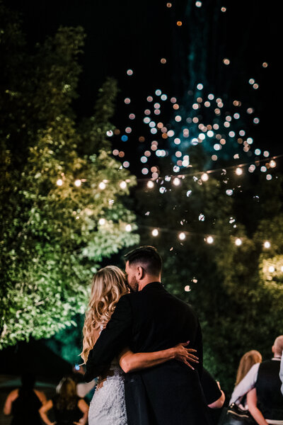 Bride and groom share a moment under twinkle lights at outdoor Pittsburgh wedding reception