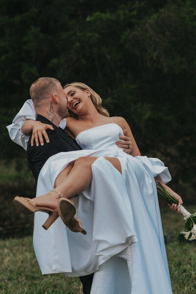 Heavily tattooed man holds his wife in his arms