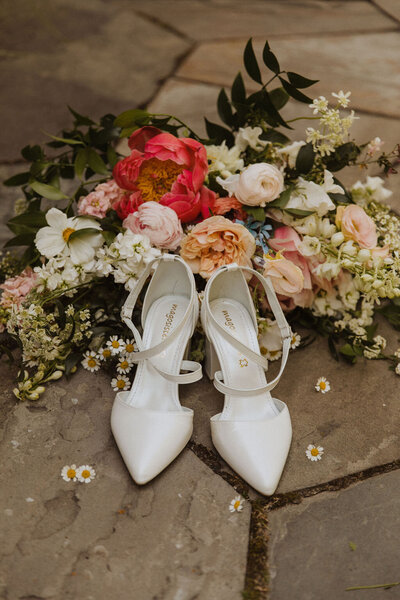 White bridal shoes with bridal bouquet of peony and garden roses