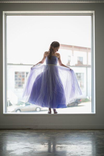 A young girl at her bat mitzvah stands in the window ledge for an artful portrait