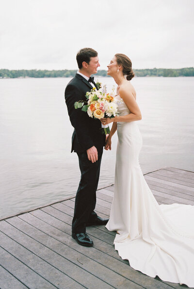 man and woman standing looking at each other on pier next to water