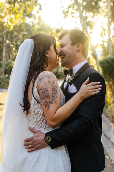 A couple romantically laughing and on the way to kiss with a golden sunset behind them, captured by Bendigo wedding photographer Tanya Strauss.