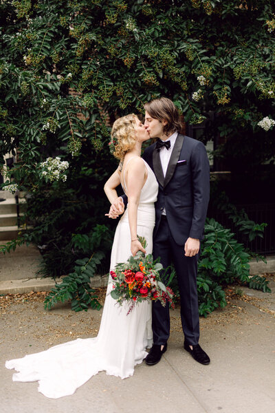 Bride and groom sharing a romantic kiss on a street in Brooklyn, New York, during their wedding day.