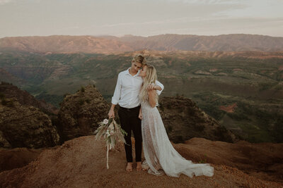 Eloping couple stands together overlooking the Waimea Canyon in Kauai