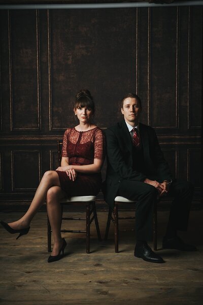 Editorial style photo booth portrait of a woman in a red lace dress and a man in a suit with a red tie
