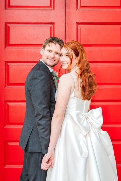 Lexington bride and groom posing in front of red doors at Gratz Park