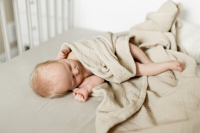Lifestyle newborn baby swaddled in crib