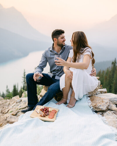 This joyful photograph captures a fiancé dancing on the frozen Lake Louise, with the fiancée gazing at her with happiness. The stunning winter landscape, with the iconic Chateau Lake Louise behind us, adds to the playful and romantic atmosphere of their engagement shoot.