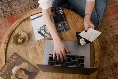 Hannah Van Woert is seated at a wooden table, engaged in work on her laptop.