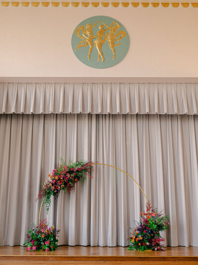 A colorful floral arch for a wedding ceremony sits on the art deco stage of the Civic Center Hall of Mirrors in Oklahoma City, Oklahoma.