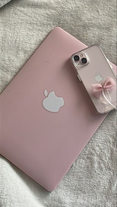 Pink Macbook and pink iPhone with bow accessory on the back
