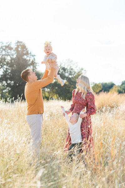 a family stands in a field of tall grass during their Austin family photography session.