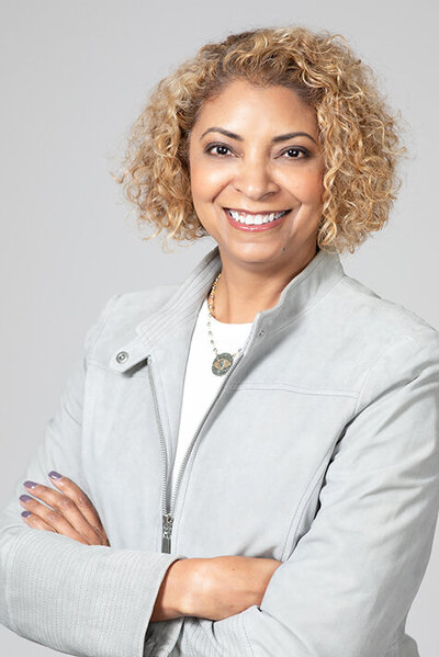 Headshot of Jennifer Richmond. She is a woman with short, curly blonde hair, brown eyes, and is wearing a gray jacket over a white shirt.