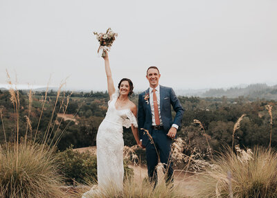 bride and groom cheering outdoors