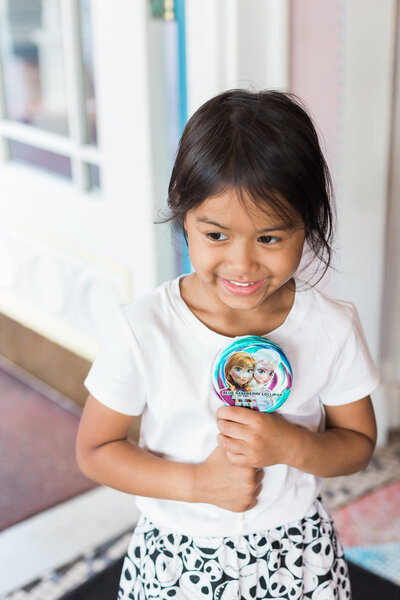 little girl smiling while holding Frozen candy at Disney