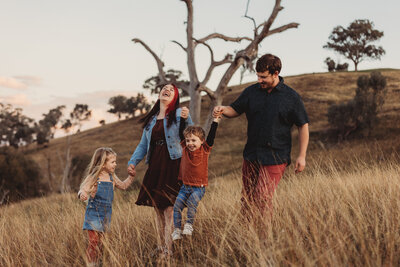 Mum and dad swinging their laughing kids in the air during a family photo session at Huon Hill with Heartfully Captured.