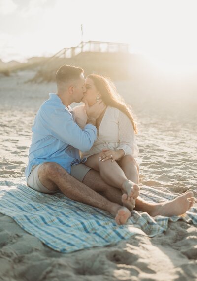 engaged couple kissing in the sand