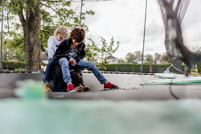 Two brothers playing with their dad and sitting on him