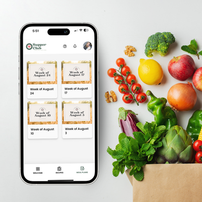 Smartphone displaying the Supper Club meal planning app with weekly menus, next to fresh produce spilling from a grocery bag.
