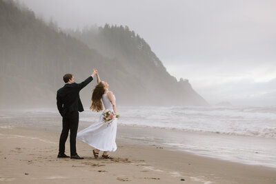 Bride spinning while groom holds her hand on the Oregon Coast.