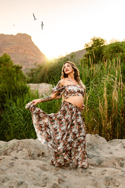 Maternity mom holding belly while standing on a rock in Phoenix, Arizona