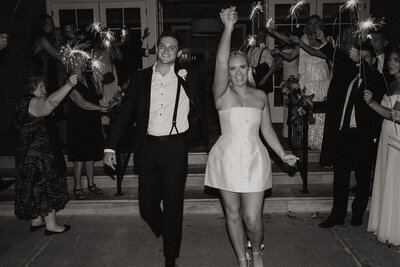 A photo of a bride and groom walking out to their reception