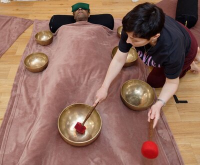 Leslie en train de pratiquer un massage sonore "Cocon" avec 7 bols népalais sur un client. 