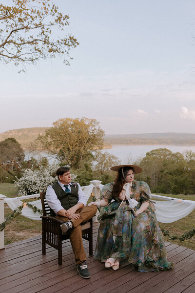 An eloping couple sits on the porch of a home on Greers Ferry Lake in Arkansas. The lake can be seen in the background.